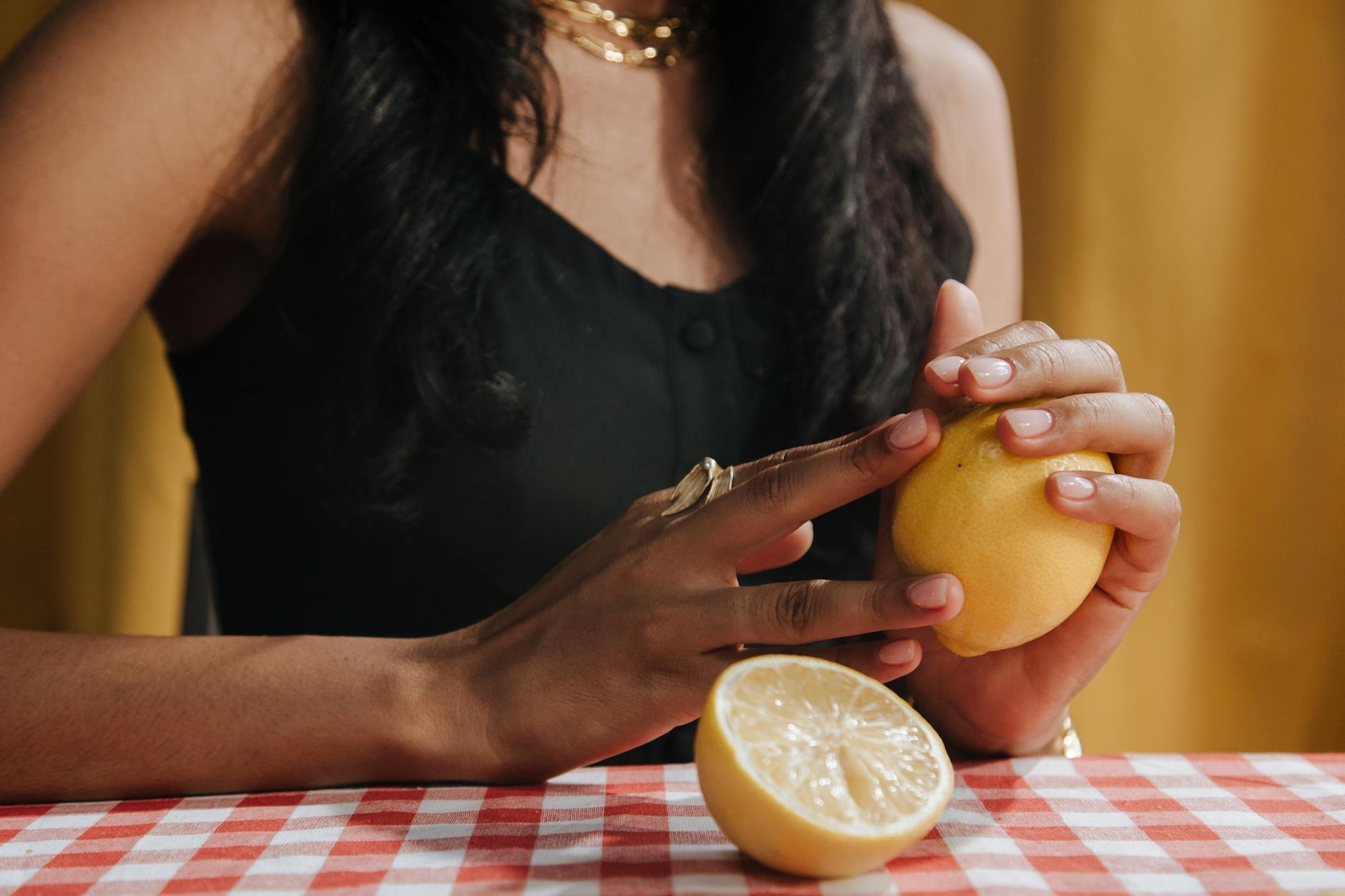 A hand holding a blue silicone lemon vibrator against a purple background