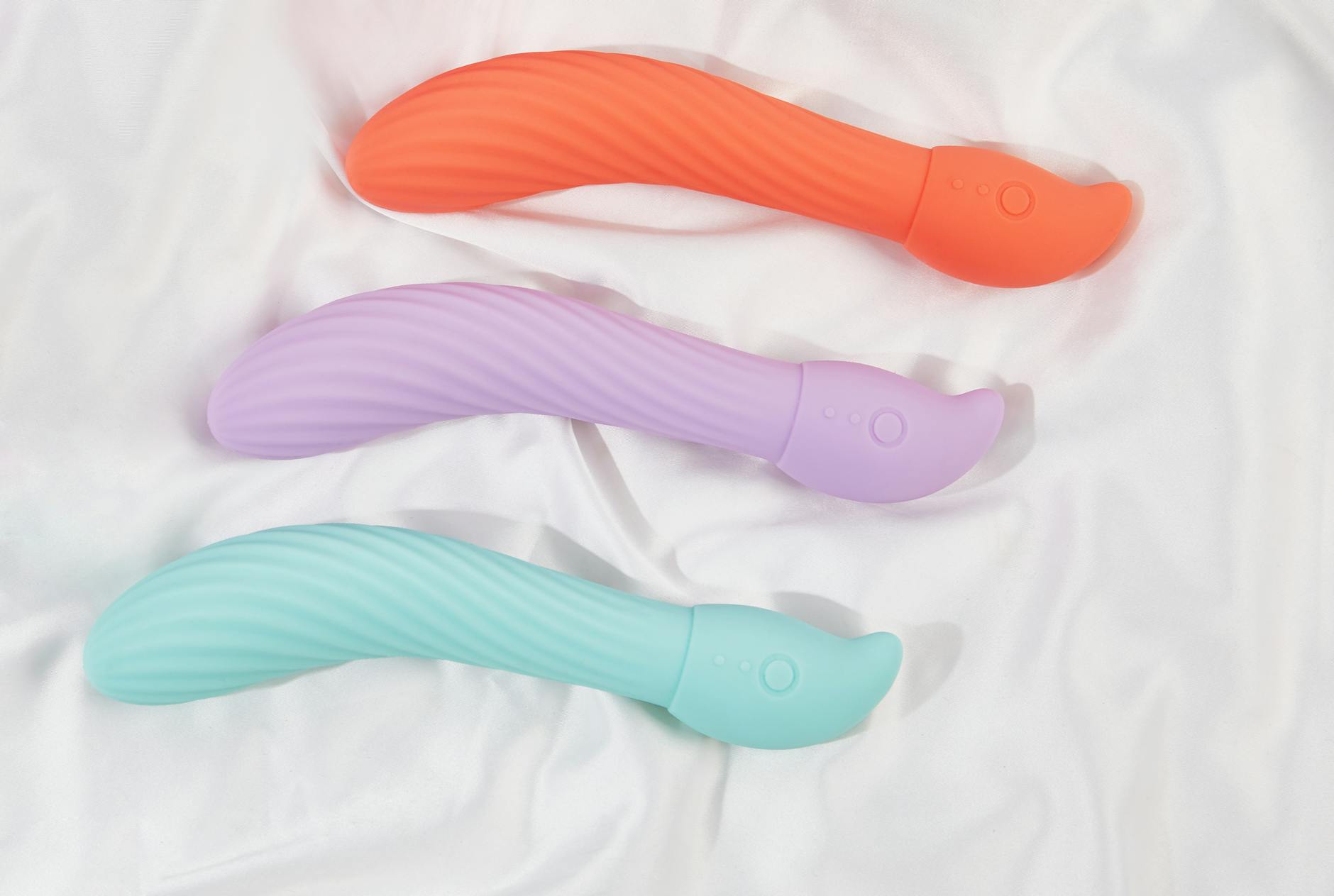 Three colorful lemon-shaped vibrators arranged on white fabric