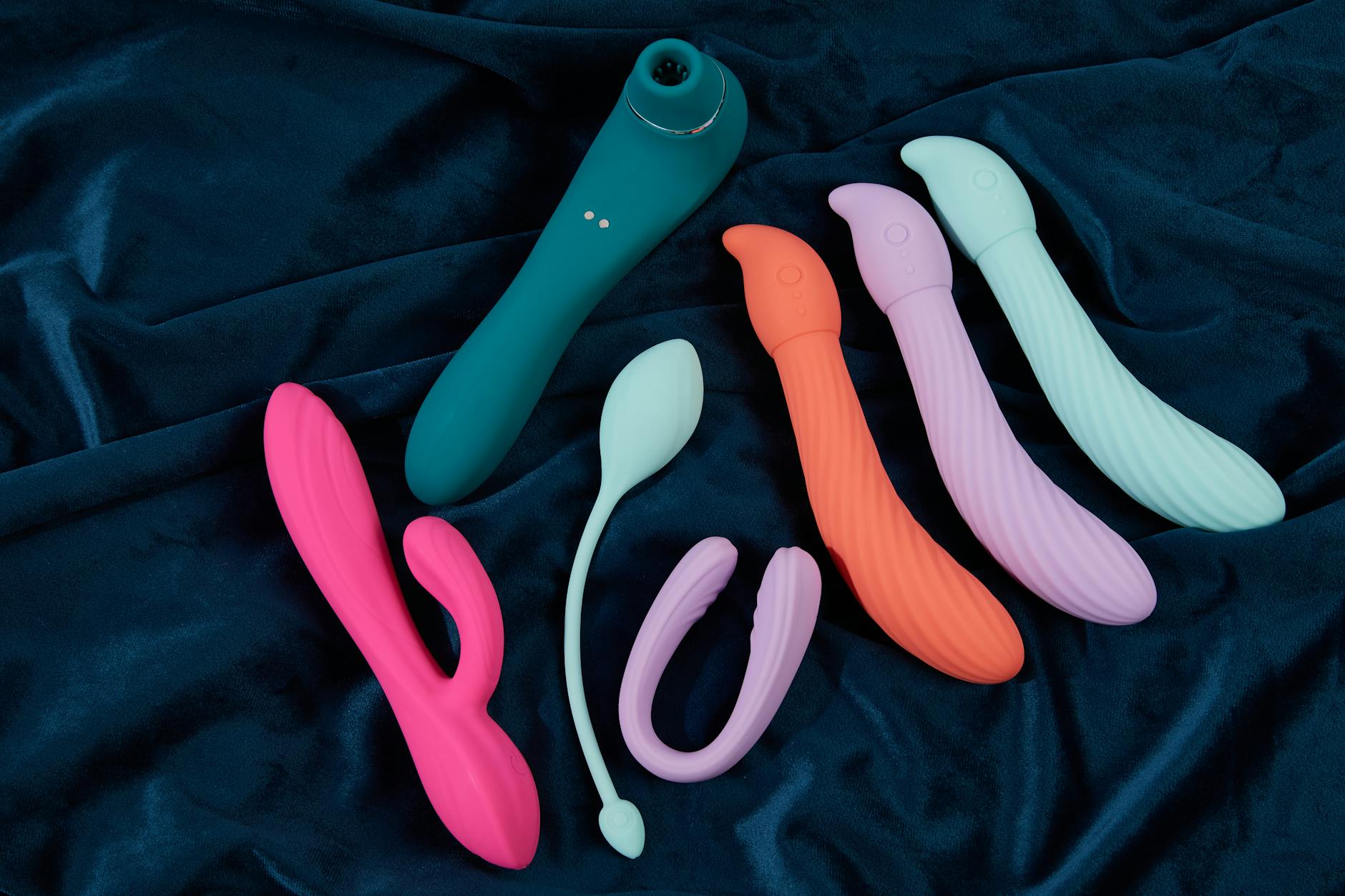 A blue silicone vibrator held in hand against a purple background, representing self-love and recovery