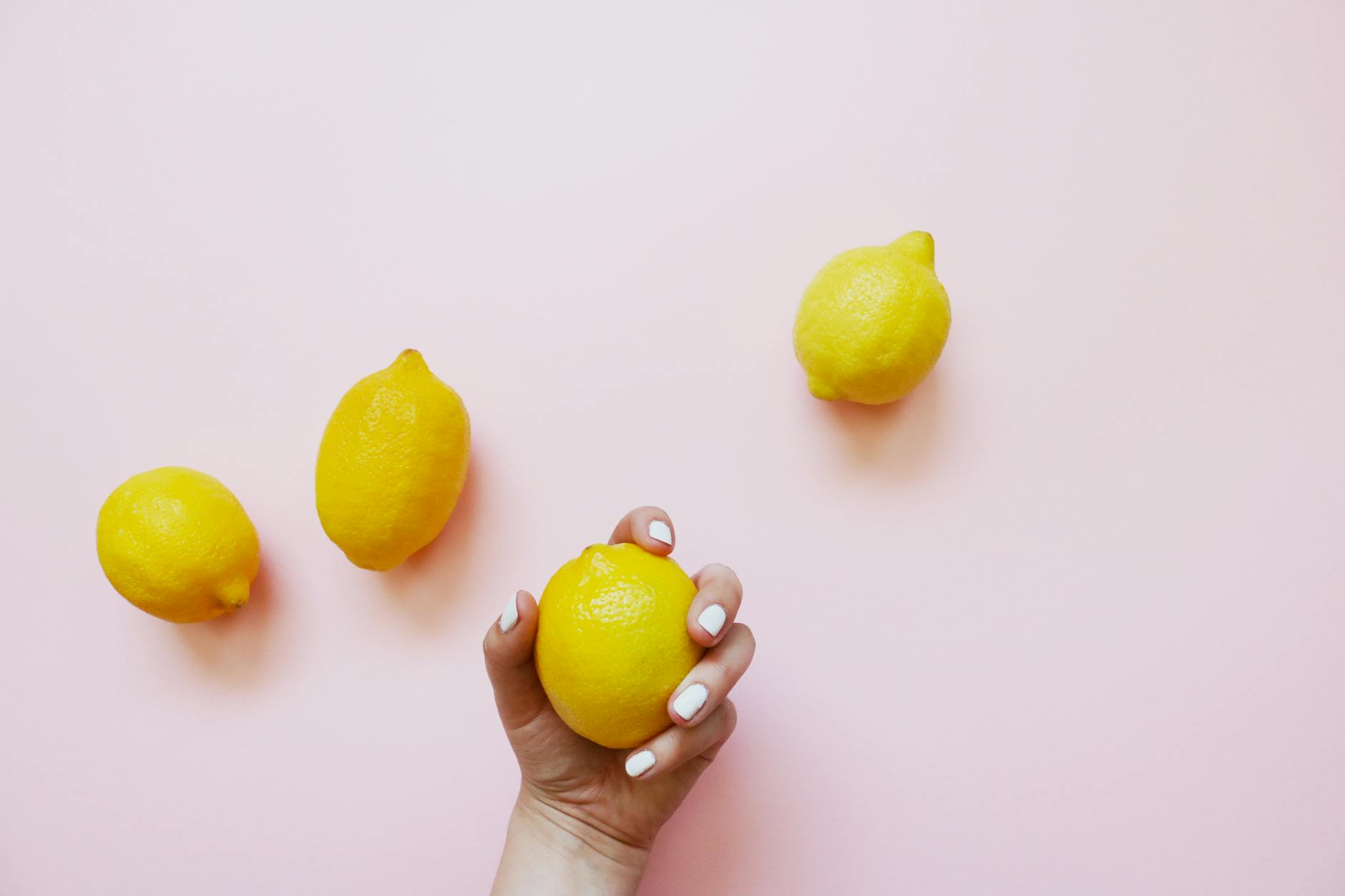 A hand holding a fresh lemon against a bright yellow background, representing a fresh start and renewal.