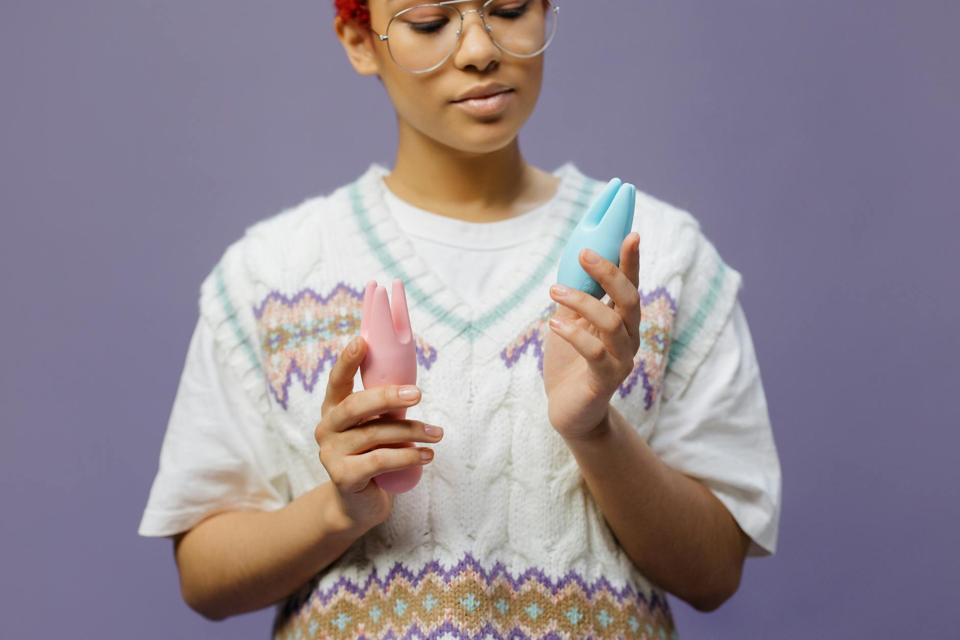 Woman holding modern clitoral vibrators while considering pleasure options