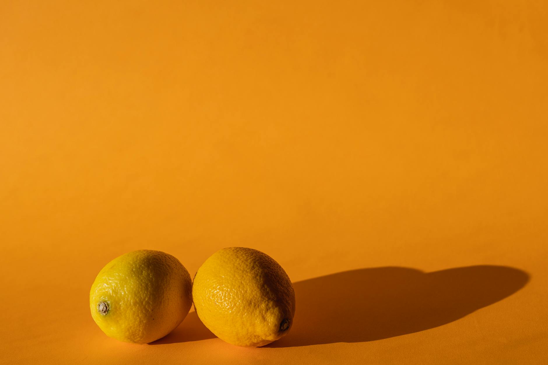 Bright yellow lemons arranged on a vivid yellow background in studio lighting